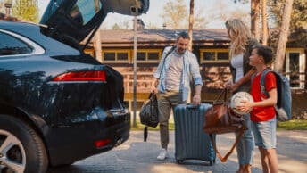 Une famille en train de préparer leur voiture avant leur départ en vacance