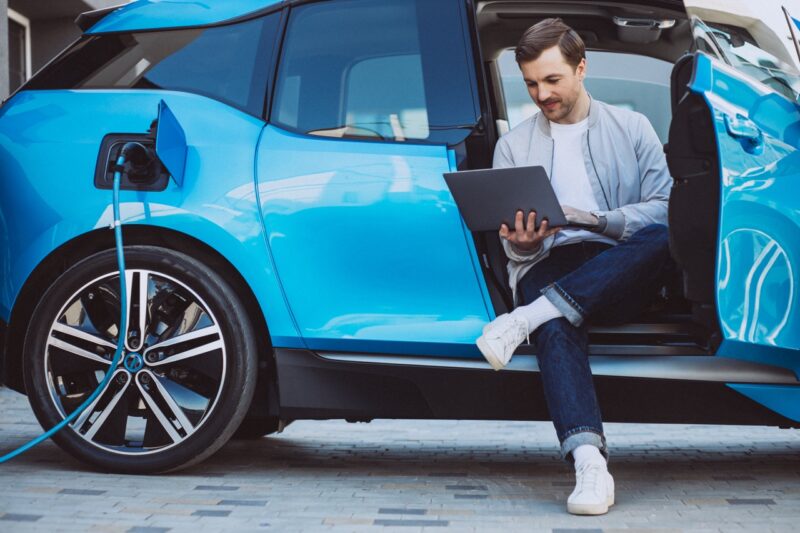 Un homme qui pratique l'éco-conduite, avec sa voiture électrique et en faisant du covoiturage.