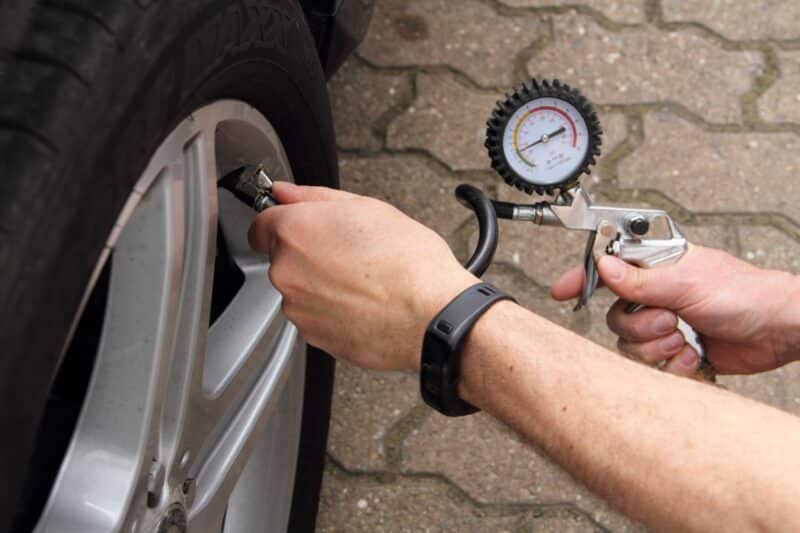 Vérification de la pression des pneus d'une voiture à l'aide d'un gonfleur avec manomètre