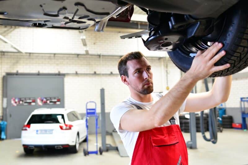 Un professionnel dans un centre automobile en train de vérifier un pneu 4 saisons qu'il vient de monter sur une voiture