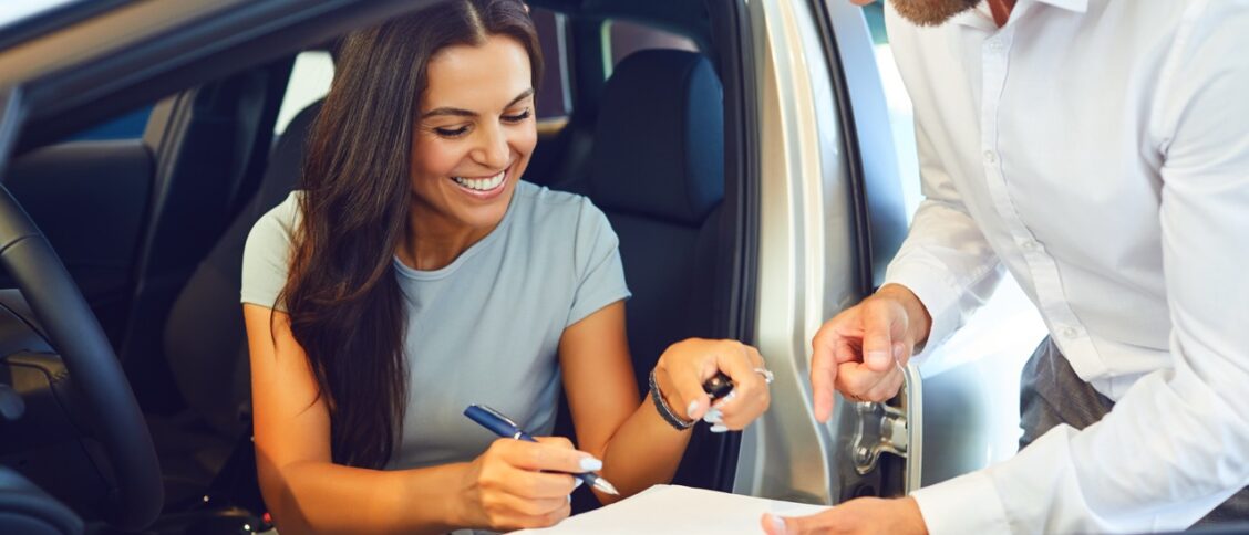 Une femme en train de signer les documents de la location d'une voiture