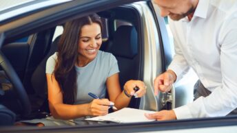 Une femme en train de signer les documents de la location d'une voiture