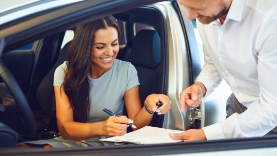 Une femme en train de signer les documents de la location d'une voiture