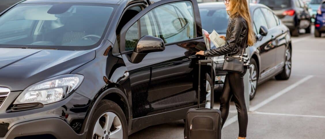 Une jeune femme récupère une voiture qu'elle vient de louer lors de ses vacances