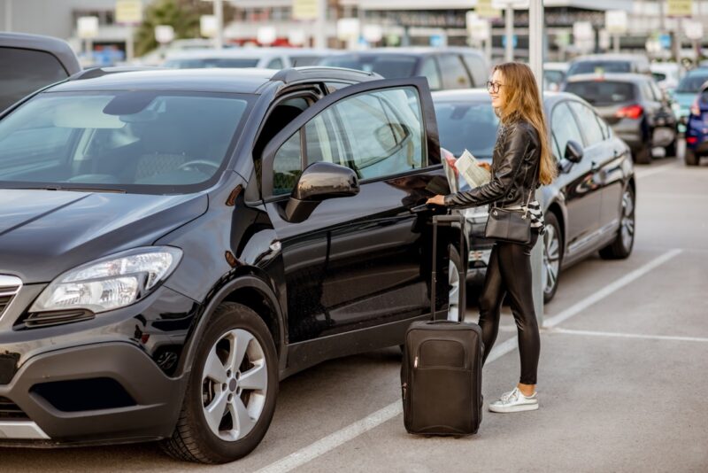 Une jeune femme récupère une voiture qu'elle vient de louer lors de ses vacances
