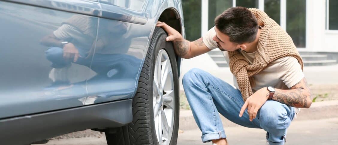 Un homme en train de vérifier les pneus de sa voiture