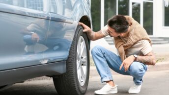 Un homme en train de vérifier les pneus de sa voiture