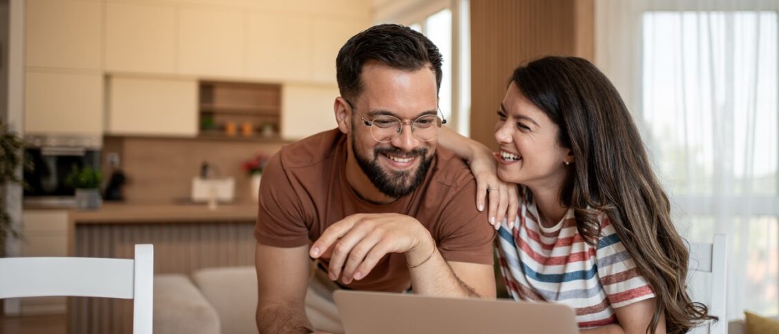 Un couple dans leur salon en train de recherche une nouvelle assurance pour leur voiture