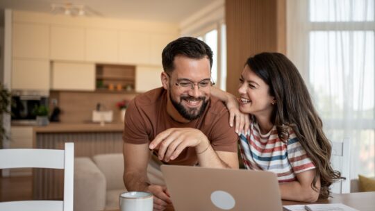 Un couple dans leur salon en train de recherche une nouvelle assurance pour leur voiture
